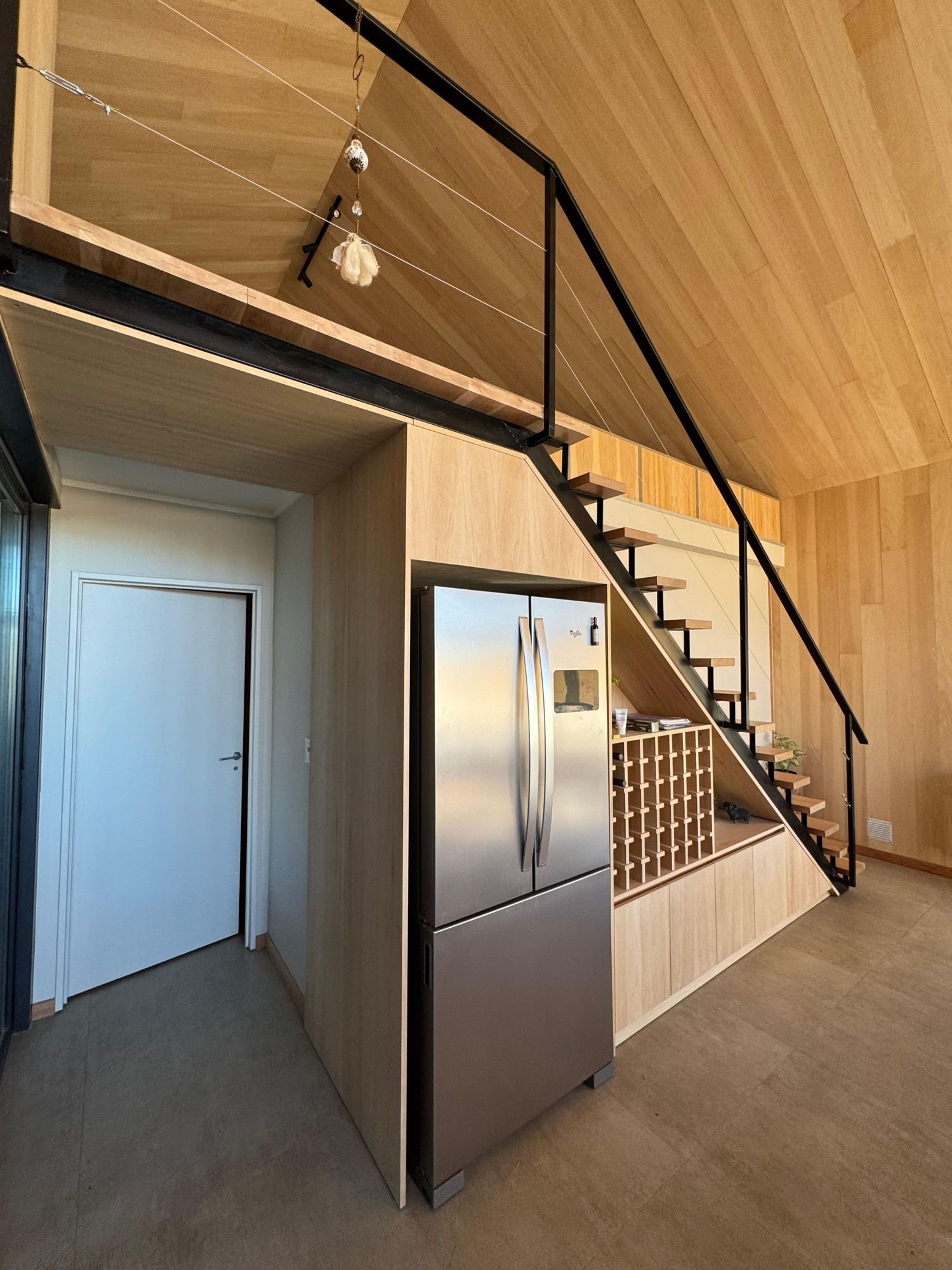 Interior de un módulo revestido en madera, con escalera metálica y entrepiso