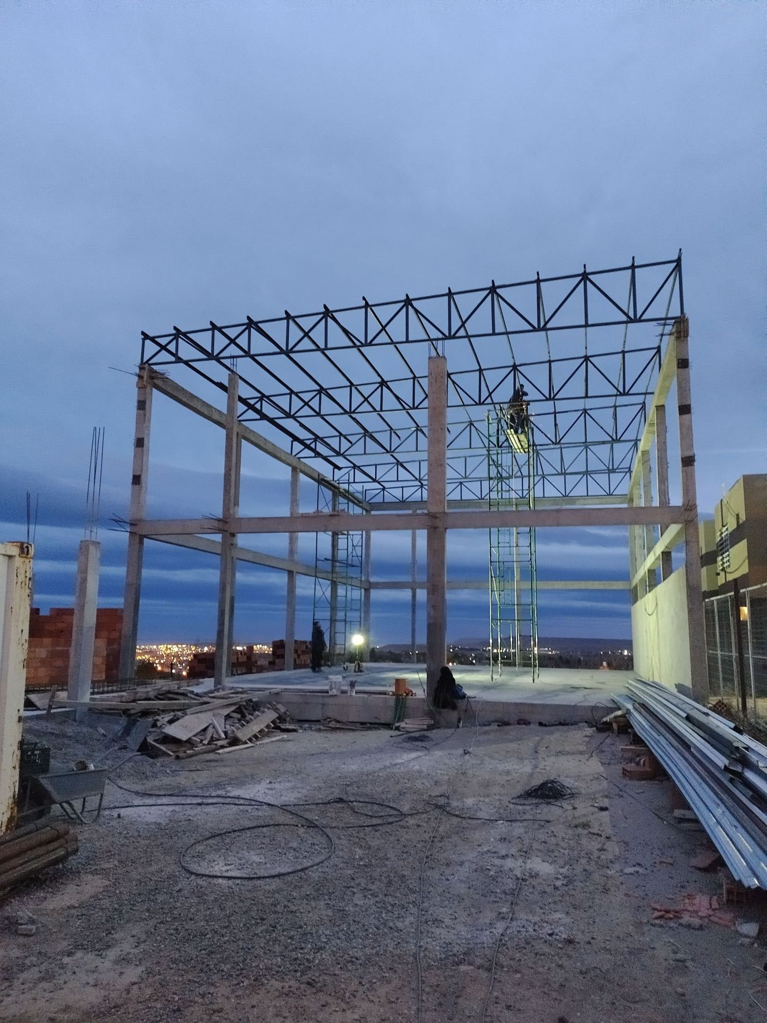 Montaje de la estructura metálica de una nave industrial al caer la tarde