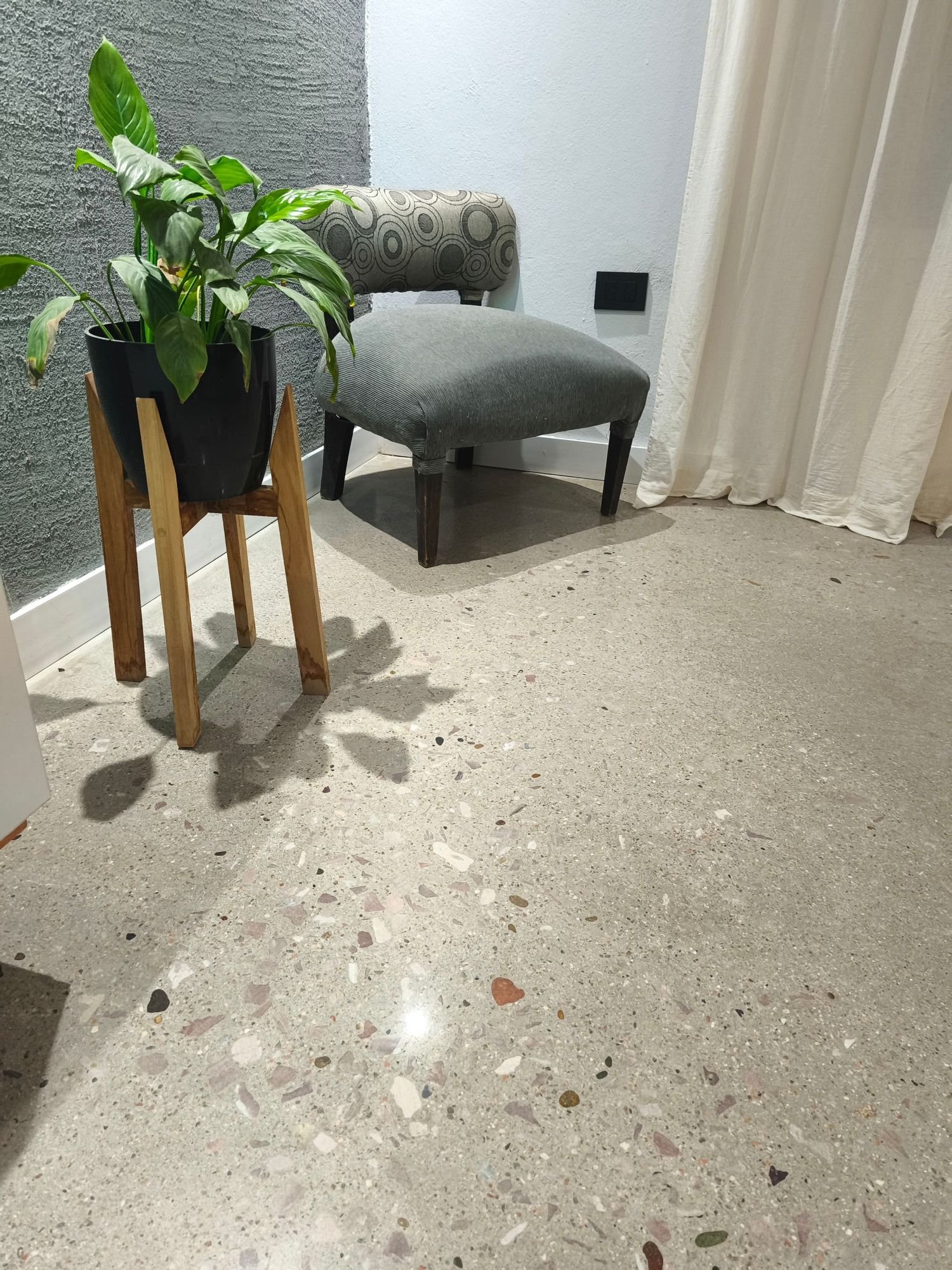 Piso de terrazo pulido en un ambiente de vivienda, con butaca y planta